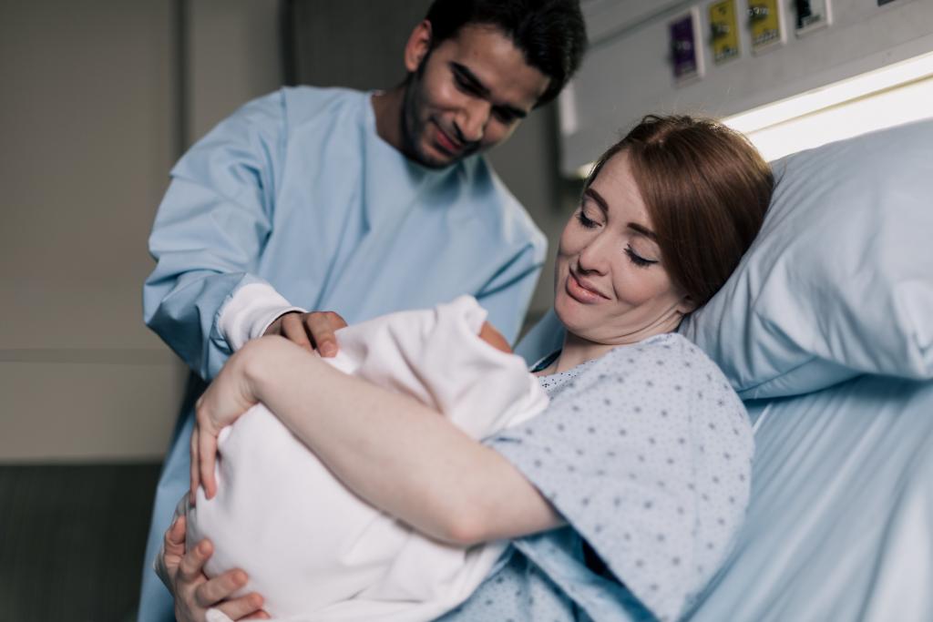 mother and father smiling down on their newborn baby 1024x683 1