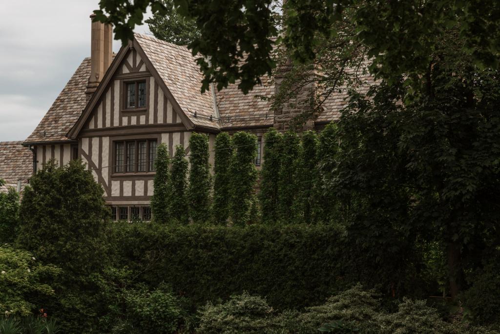 side of a brown house with tall hedges obscuring view 1024x683 1